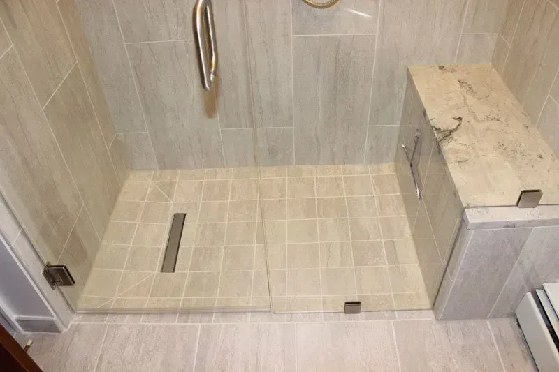 Accessible tiled shower with a low threshold, grab bar, and built-in bench seat In Bucks County PA