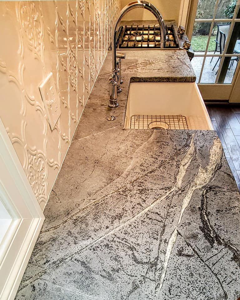 Kitchen countertop with sink, faucet, and granite surface by a window and decorative wall In Bucks County PA