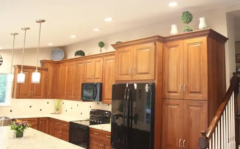Warm kitchen with wooden cabinets, black appliances, and pendant lights over a breakfast bar In Bucks County PA