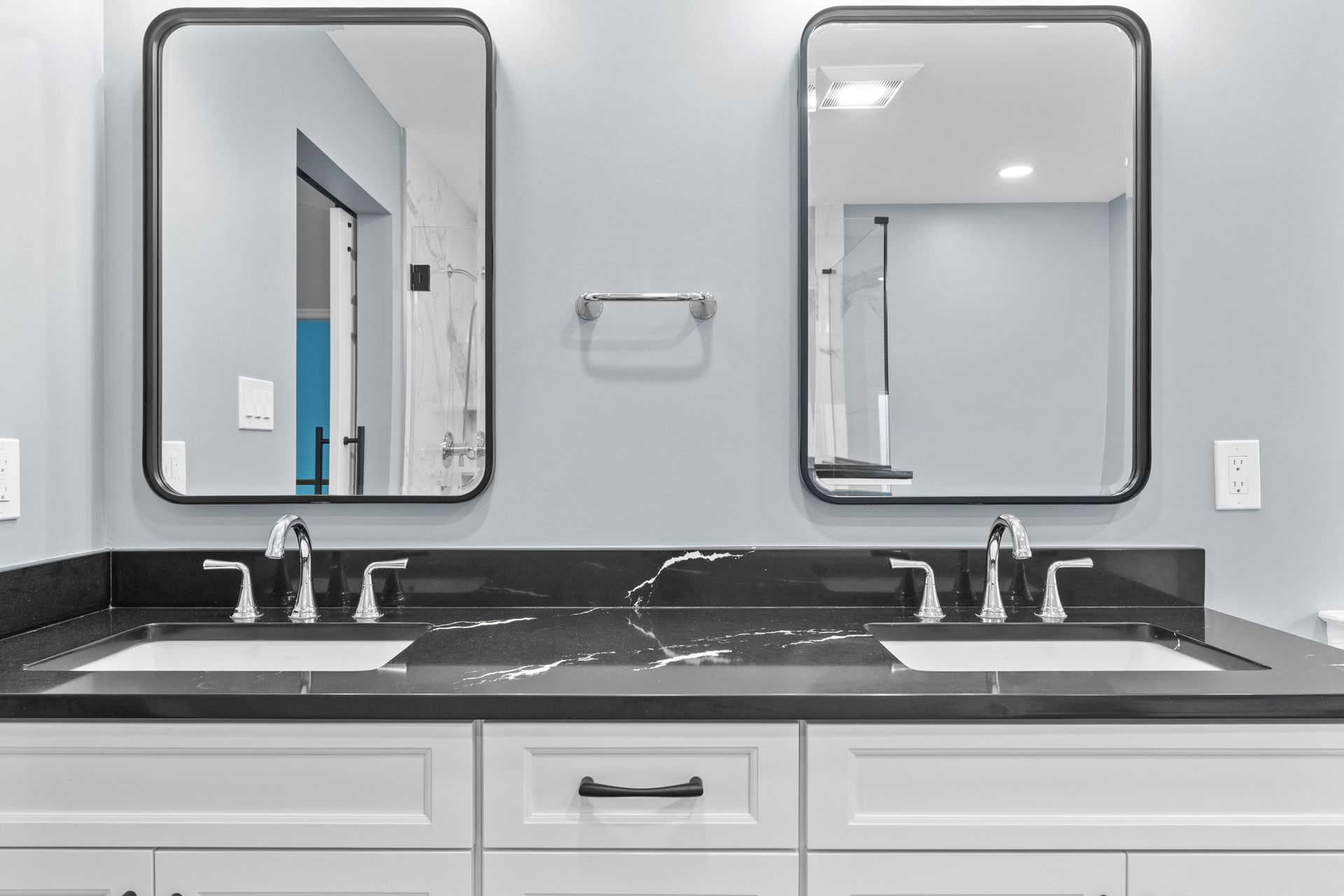 Modern bathroom vanity with double sinks, black countertops, and wall mirrors In Bucks County PA