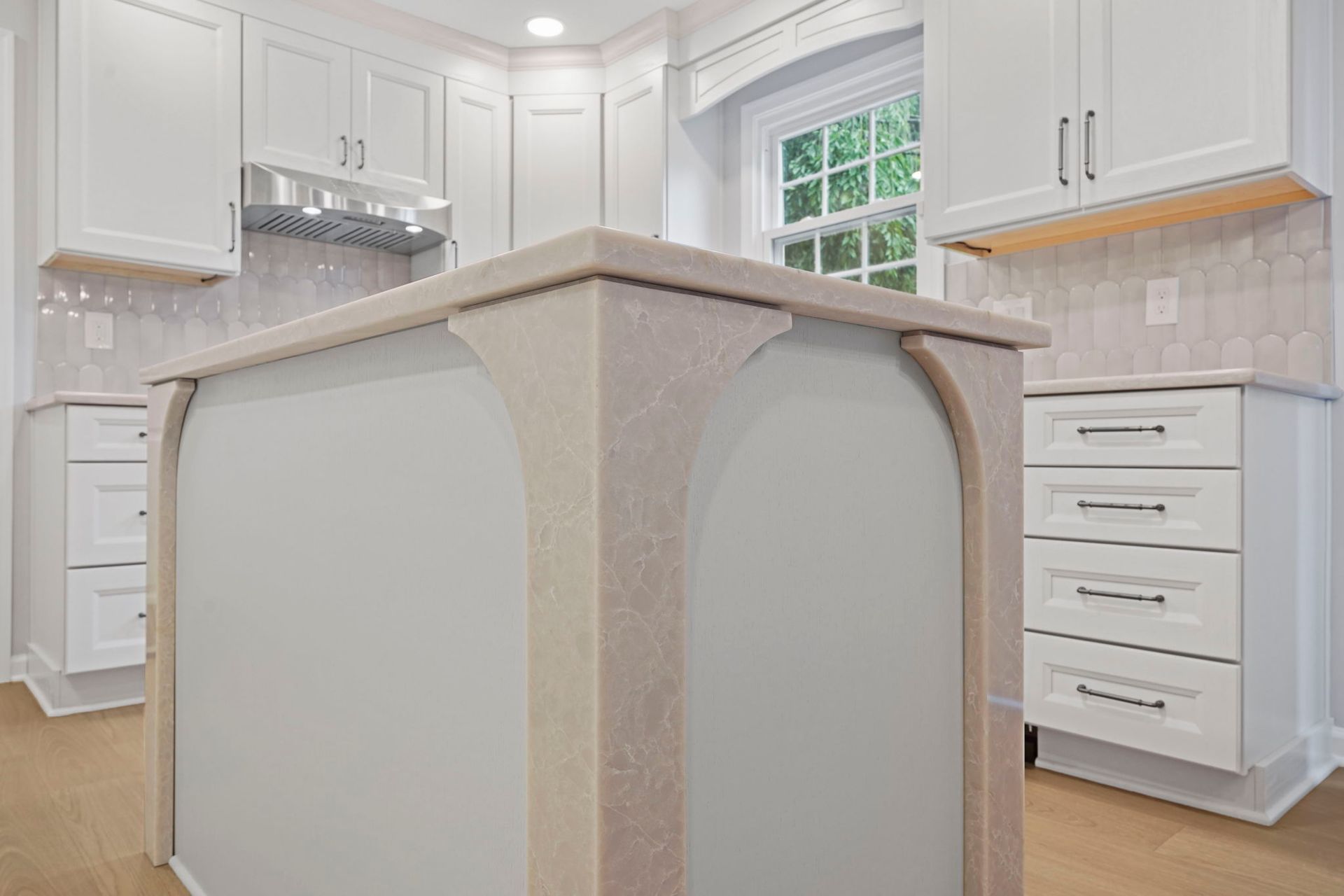 White kitchen with central island, beige countertops, and bright windows in Langhorne