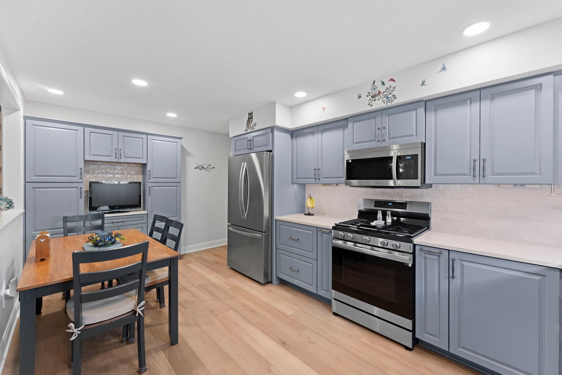 Modern kitchen with gray cabinets, stainless steel appliances, and a wooden dining table with chairs In Bucks County PA