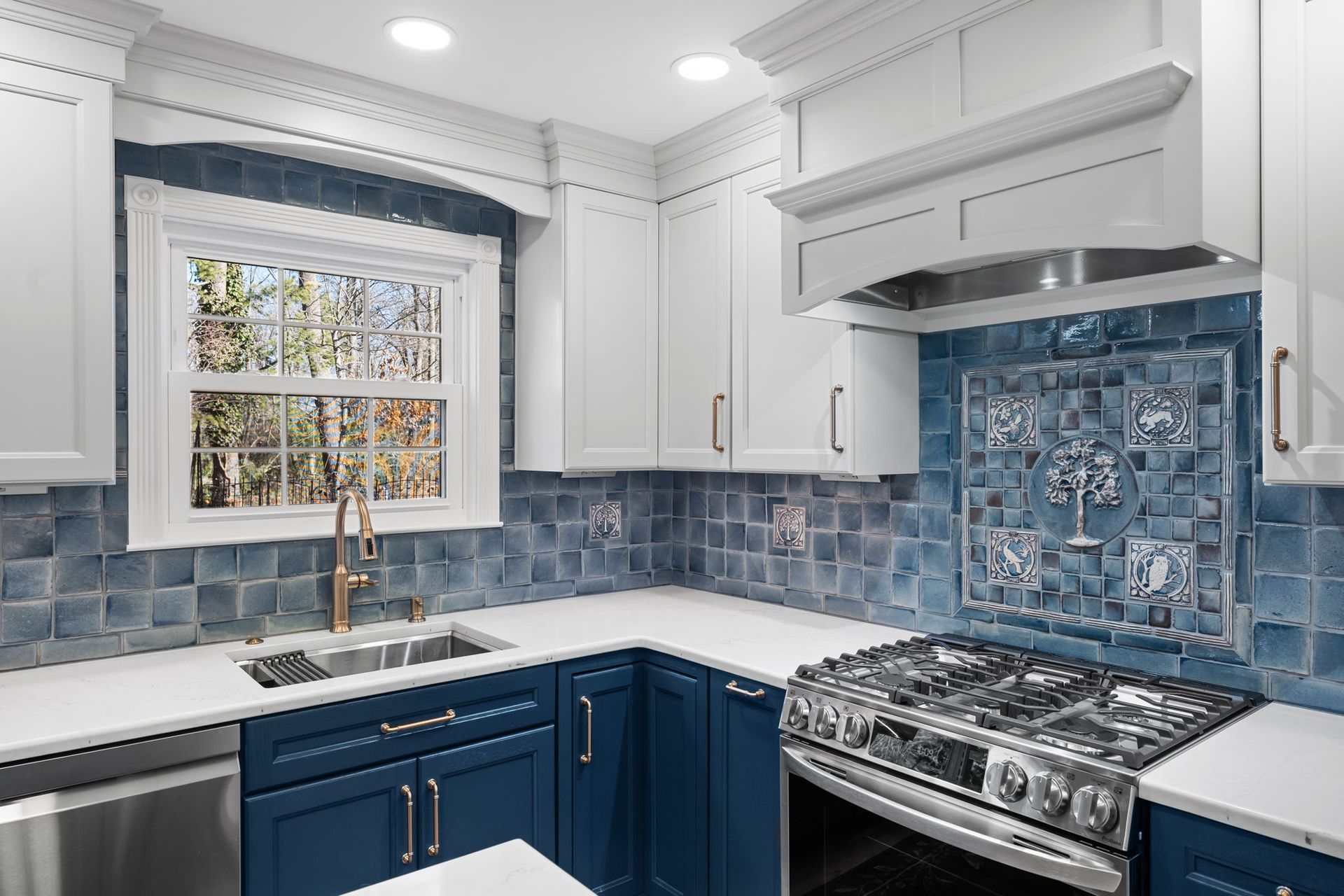 Blue-and-white kitchen with tiled backsplash, white cabinets, window, and stainless steel stove sink area  In Bucks County PA