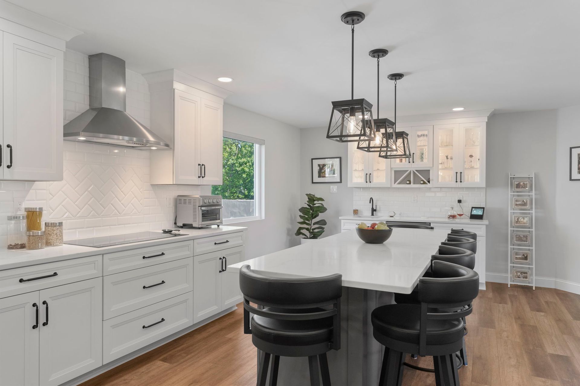 Bright white kitchen with island, black stools, pendant lights, and wood floors In Bucks County PA