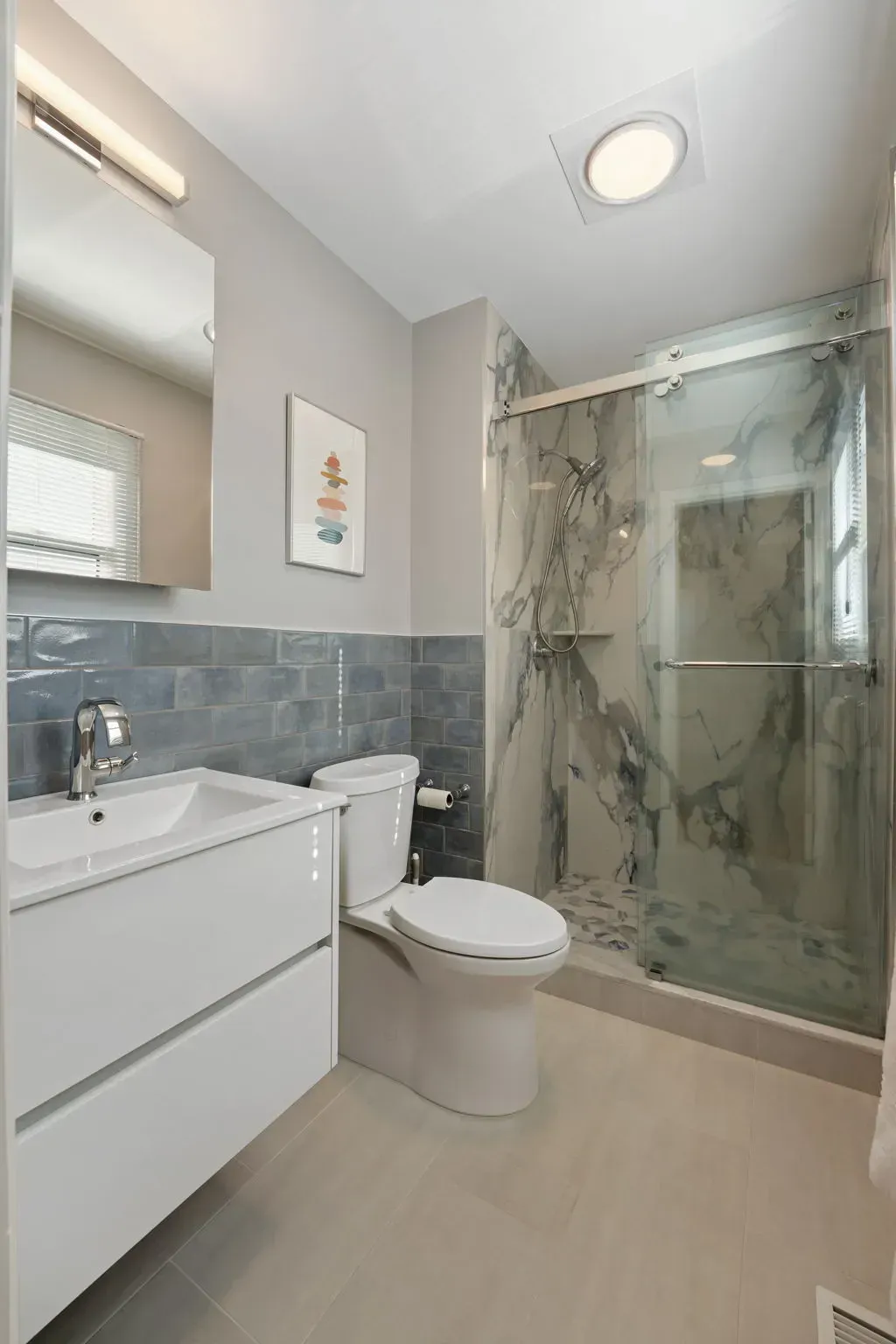 Modern bathroom with white vanity, toilet, and marble glass shower  In Bucks County PA