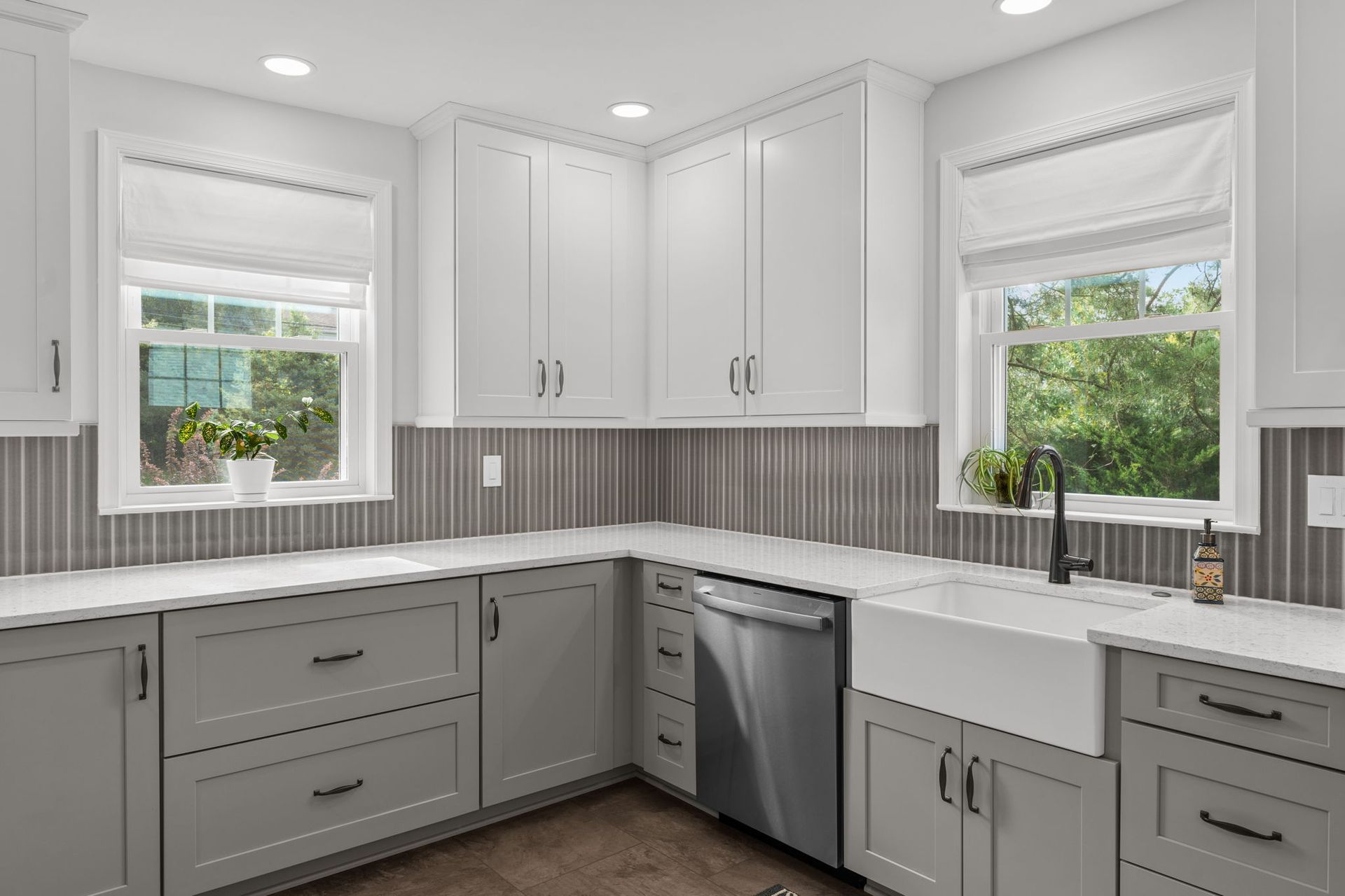 Bright gray kitchen with white cabinets, stainless dishwasher, and two windows over the counter In Bucks County PA