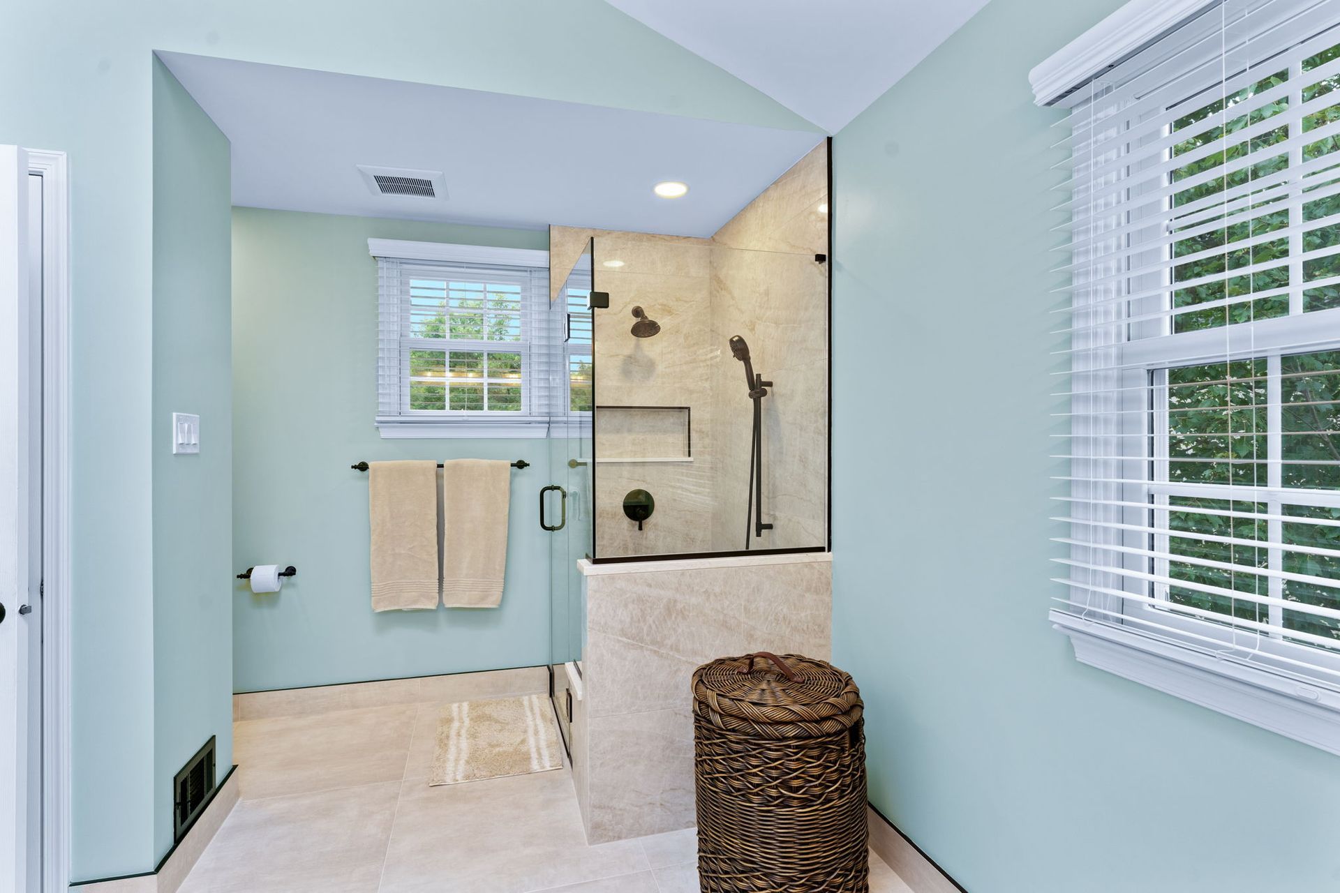 Bright bathroom with shower, towels, and window blinds in pale blue and white colors In Bucks County PA