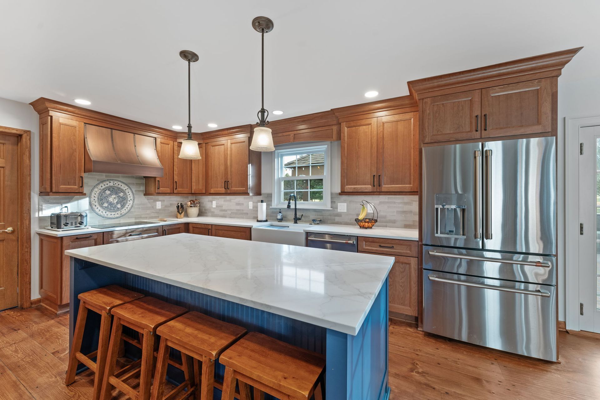 Spacious modern kitchen with wooden cabinets, large white island, and stainless steel refrigerator In Bucks County PA