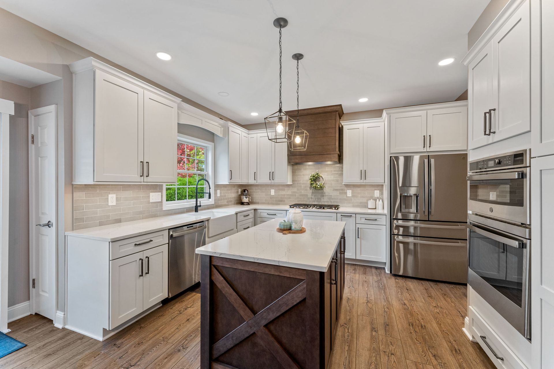 Bright white kitchen with island, stainless steel appliances, wood floors, and pendant lights  In Bucks County PA