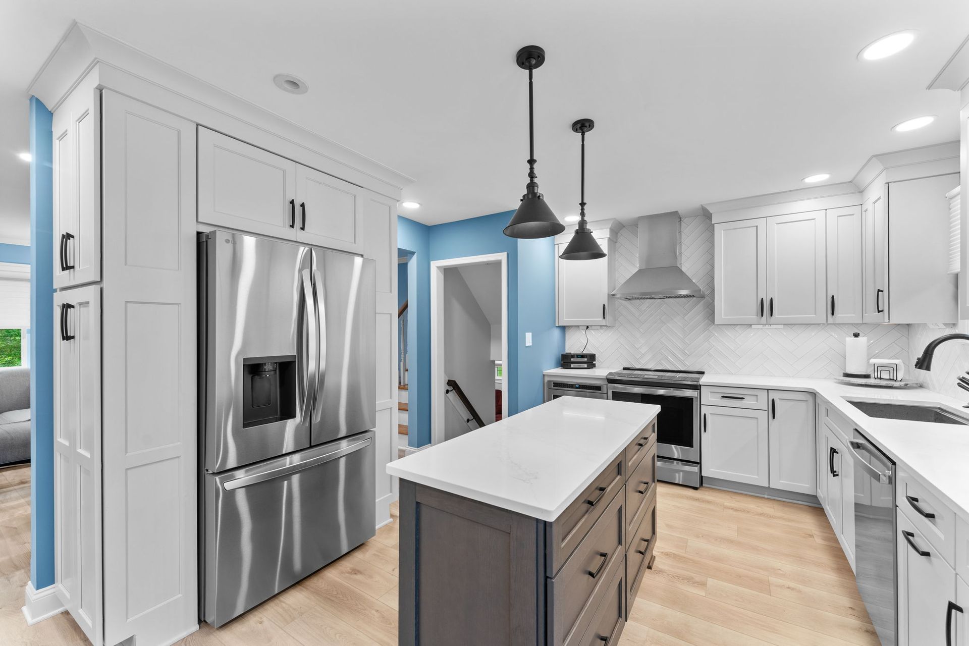 Bright modern kitchen with white cabinets, stainless fridge, island, and blue accent walls in Bucks County PA