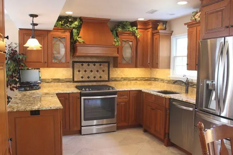 Modern kitchen with wooden cabinets, stainless steel appliances, granite counters, and a tiled backsplash In Bucks Country PA