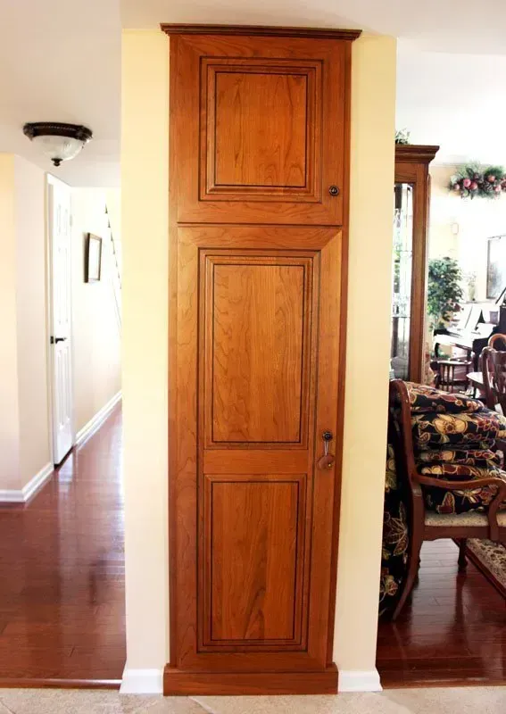 Tall wooden cabinet door in a hallway between a dining room and entryway  In Bucks County PA