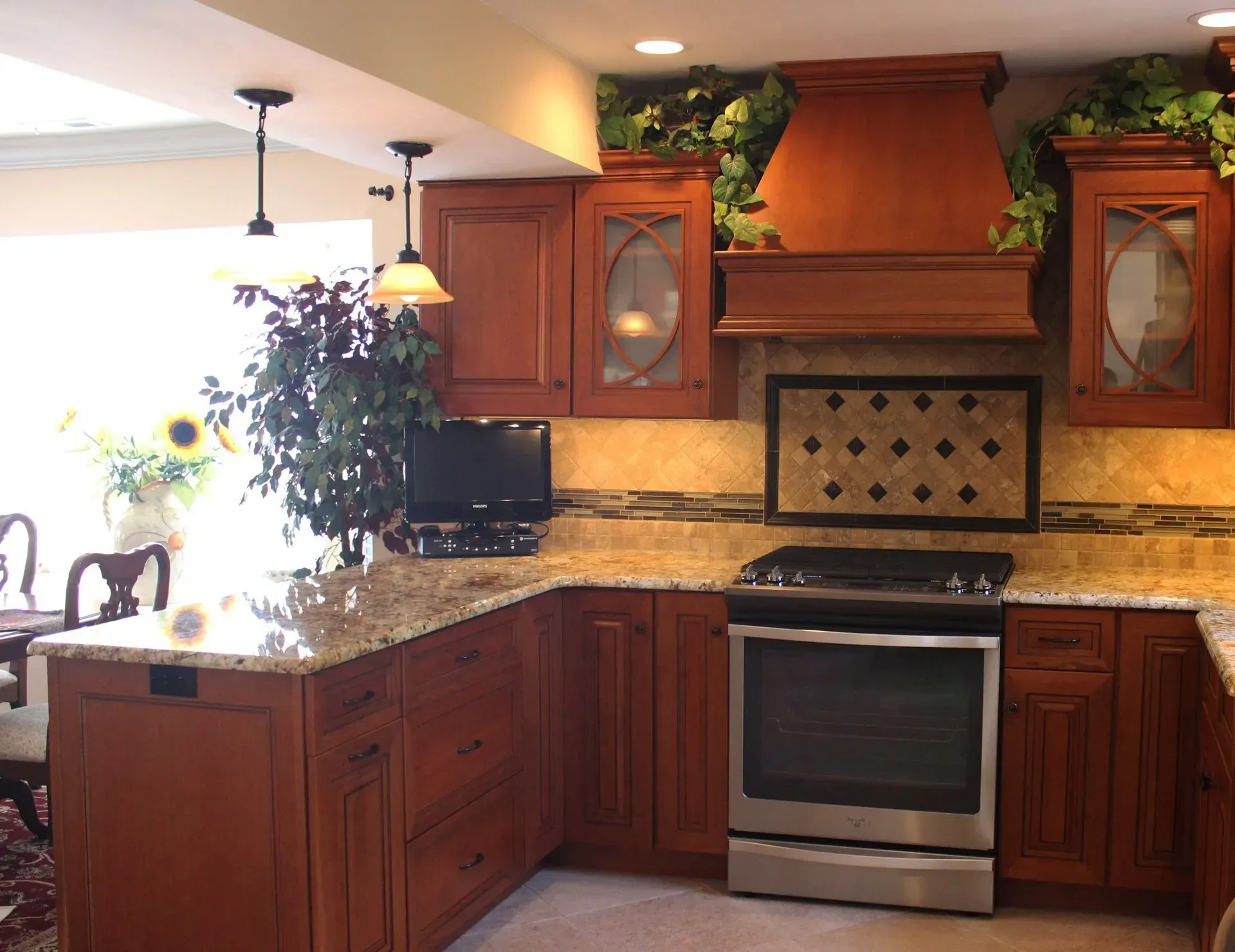 Warm kitchen with wooden cabinets, granite counters, stainless stove, and a decorative hood above the range  In Bucks County PA