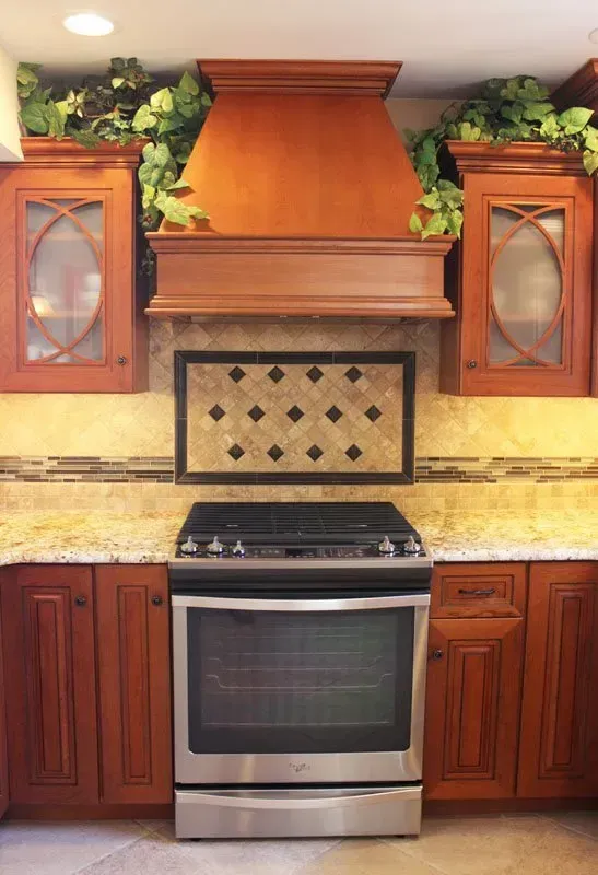 A kitchen with a stainless steel stove, wooden cabinets, and a large copper range hood  In Bucks County PA