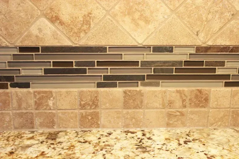 Kitchen backsplash with tan stone tiles and a speckled granite countertop  In Bucks County PA