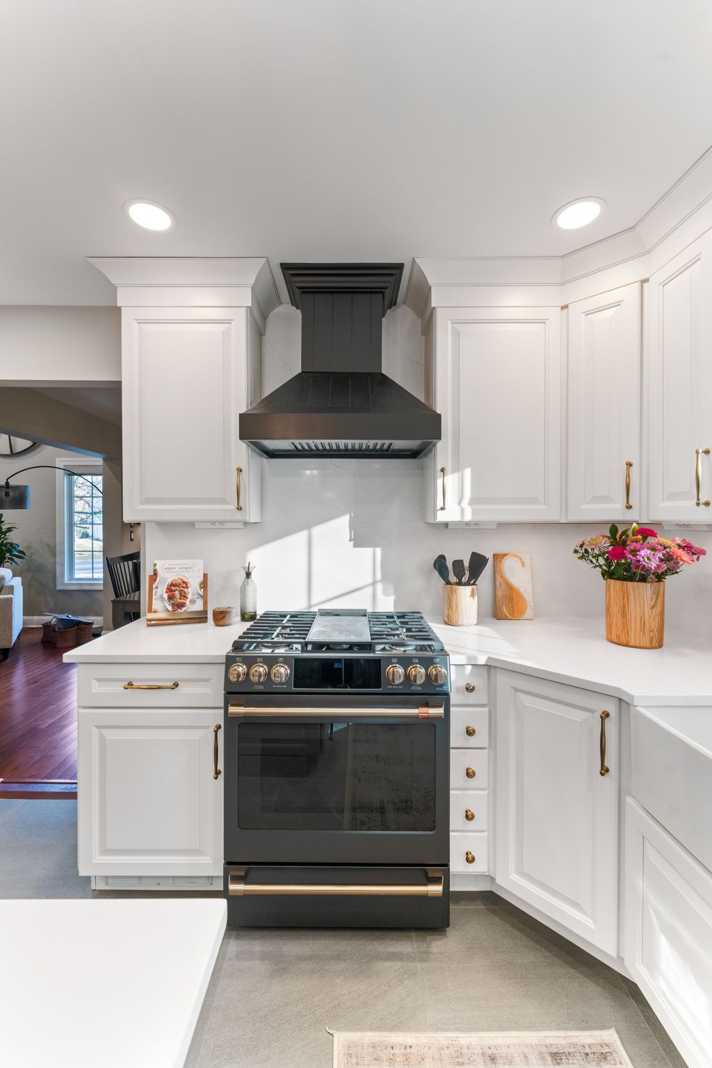 Bright white kitchen with black stove and range hood, white cabinets, and a vase of pink flowers on the counter In Bucks Country PA