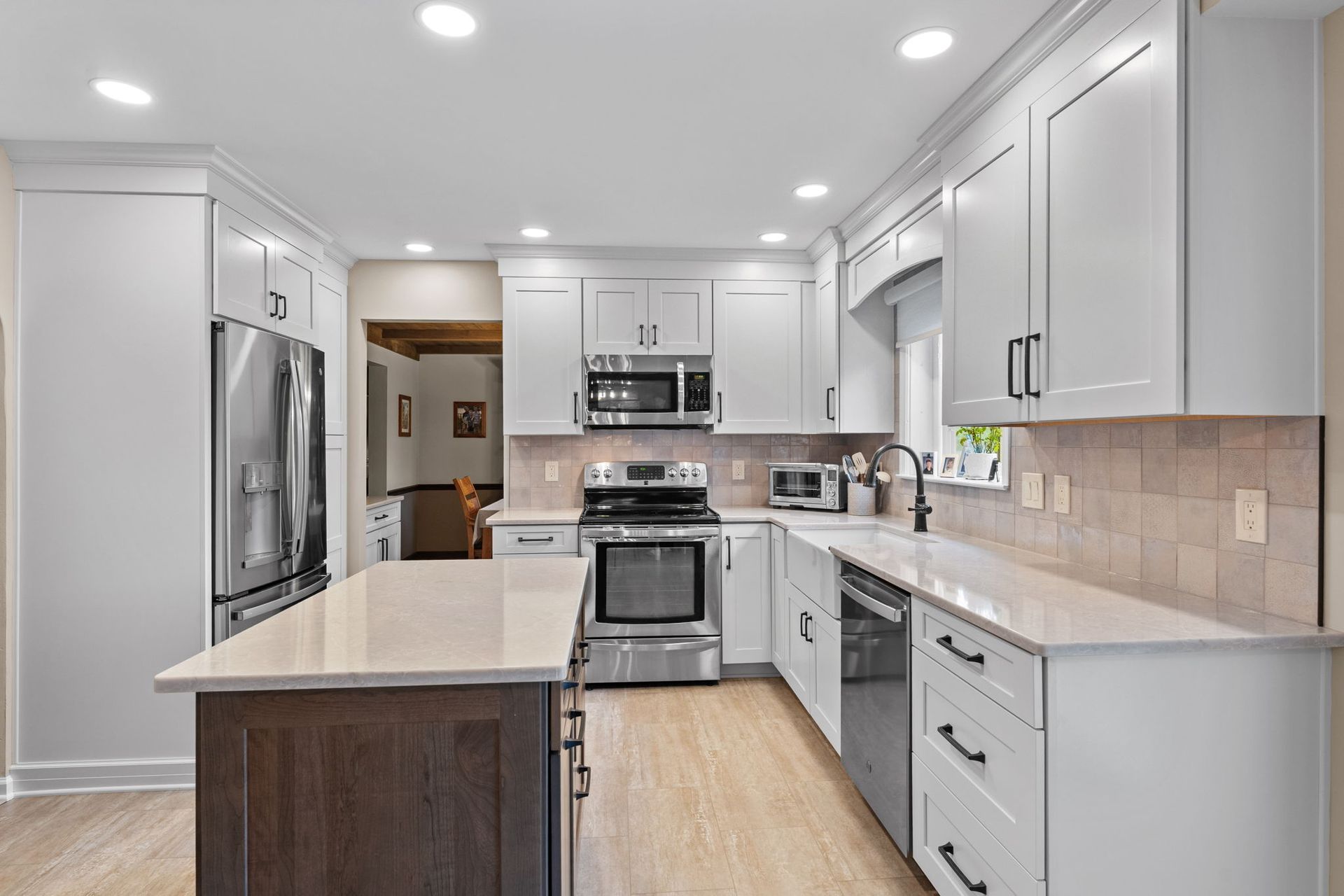 Bright modern kitchen with white cabinets, stainless steel appliances, and light wood flooring In Bucks Country PA