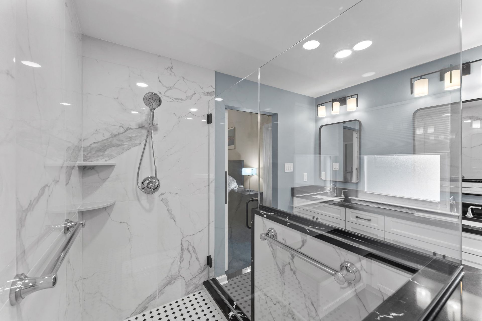 Modern white marble bathroom with glass shower, chrome fixtures, and vanity mirror In Bucks County PA