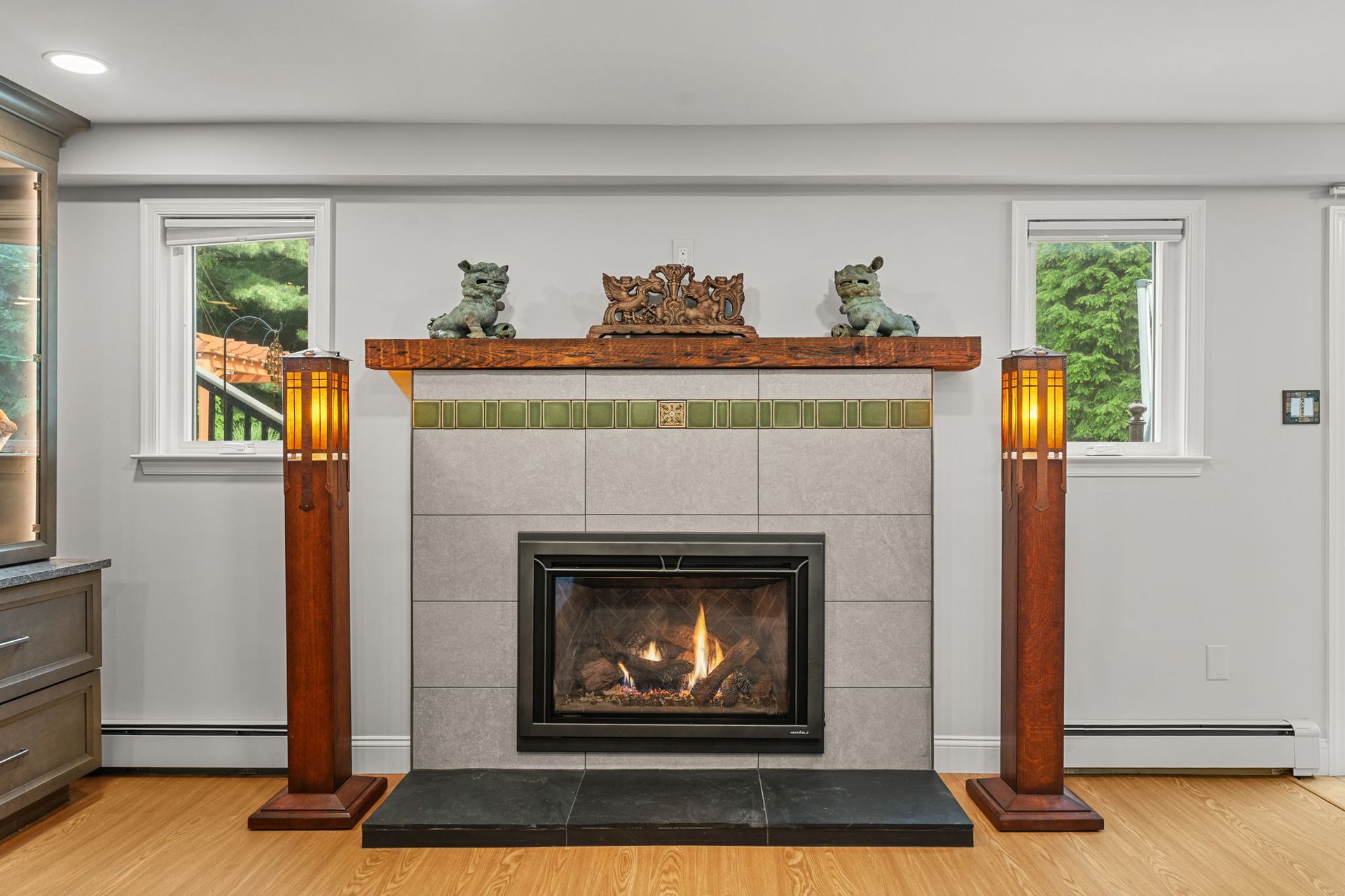 Living room fireplace with two wooden floor lamps and a brick mantel, centered between two windows In Bucks County PA