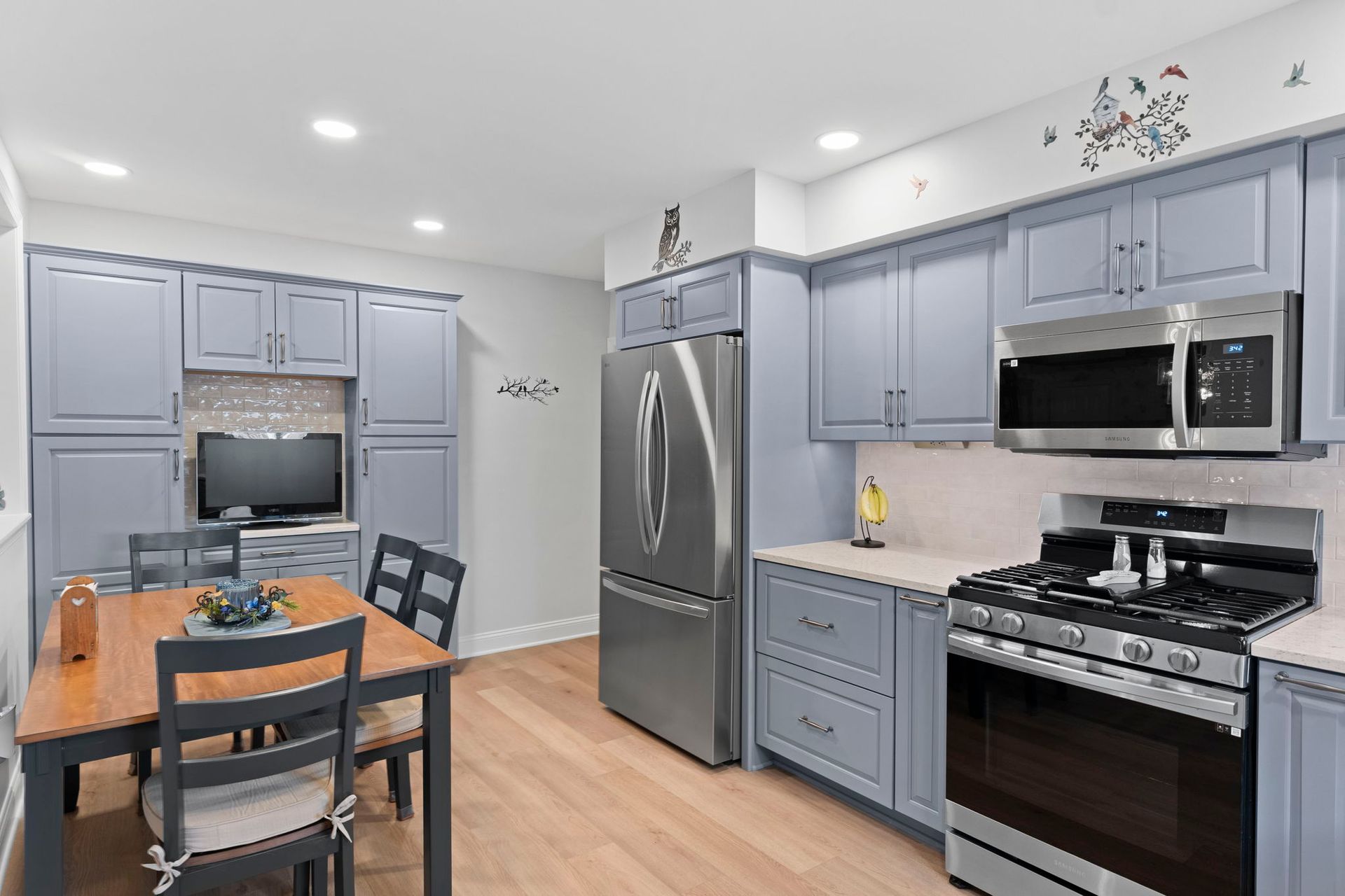 Bright modern kitchen with gray cabinets, stainless appliances, and a wooden dining table In Bucks County PA