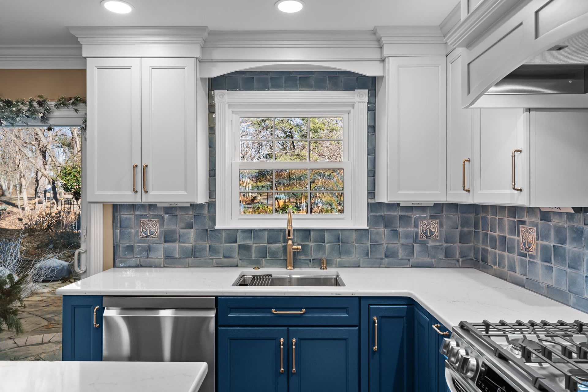 Bright kitchen with blue lower cabinets, white uppers, tiled backsplash, and a window over the sink  In Bucks County PA