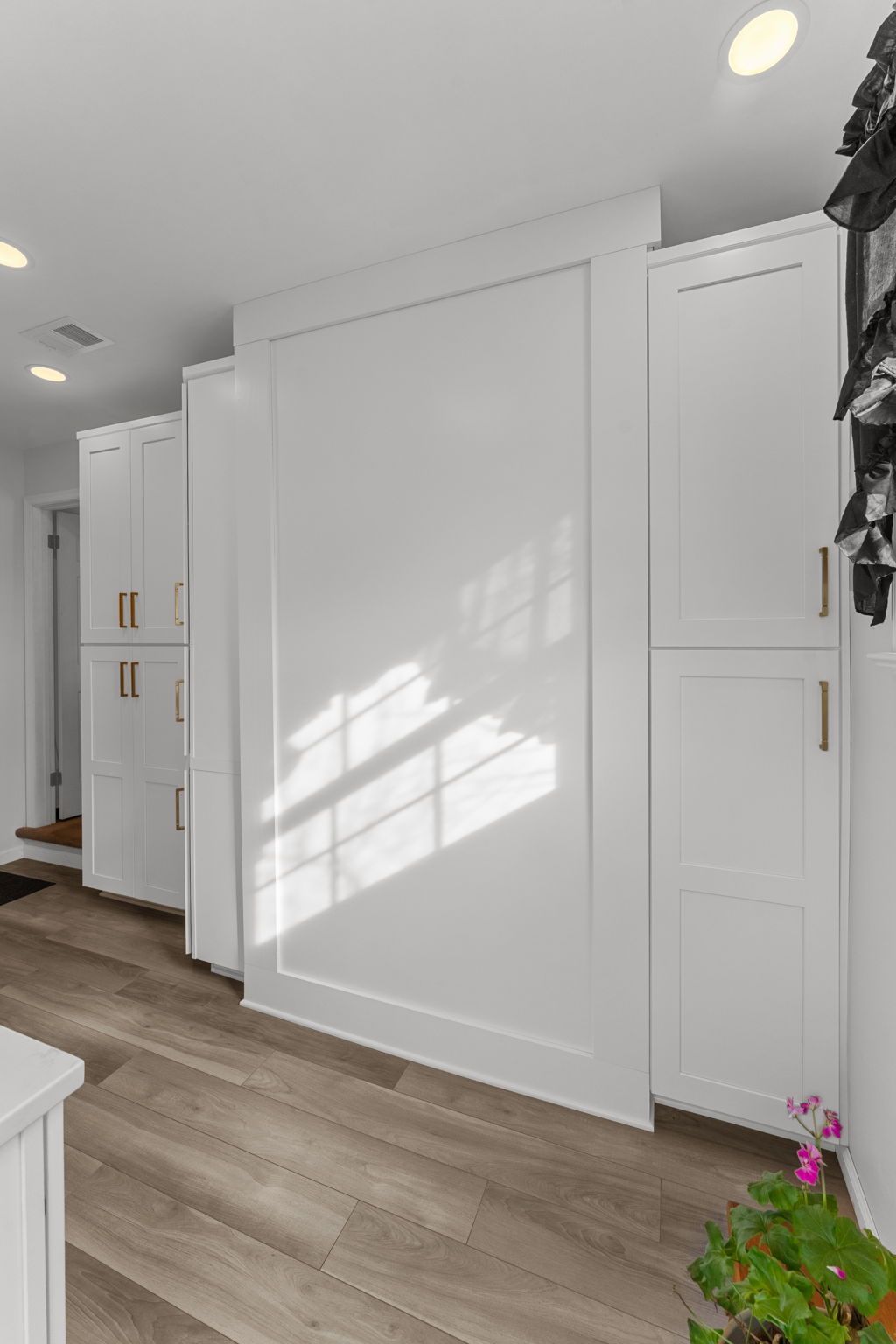 Bright hallway with white built-in cabinets, wood flooring, and sunlight on the wall In Bucks County PA