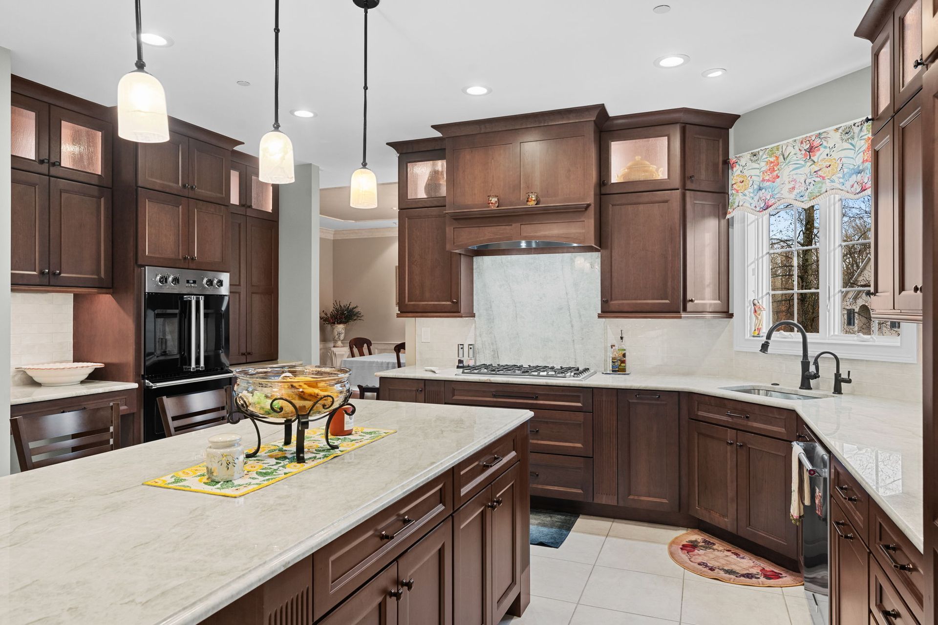 Modern kitchen with dark wood cabinets, white countertops, island, and pendant lights In Bucks Country PA