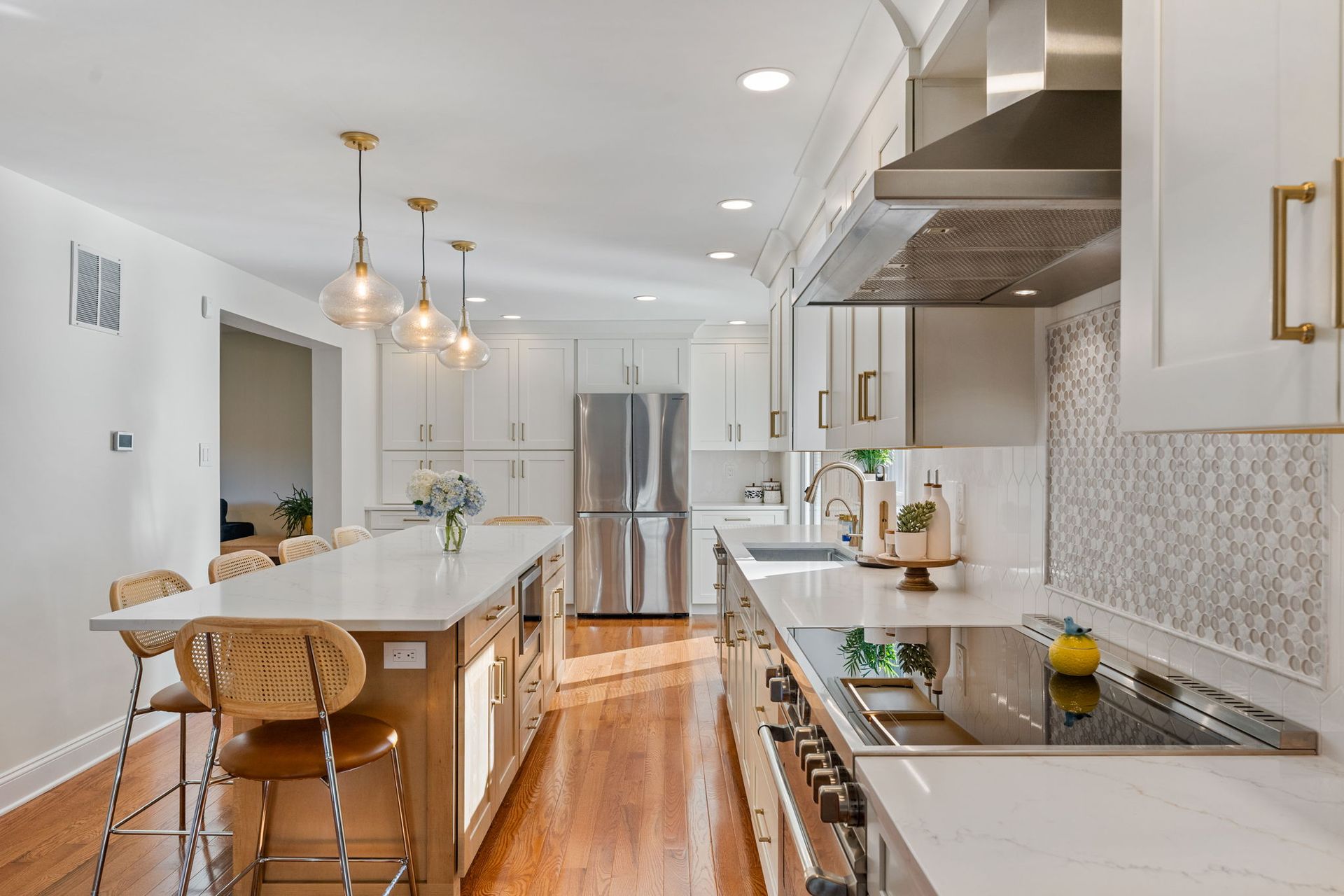 Bright modern kitchen with white cabinets, stainless appliances, island, and wooden stools In Bucks County PA