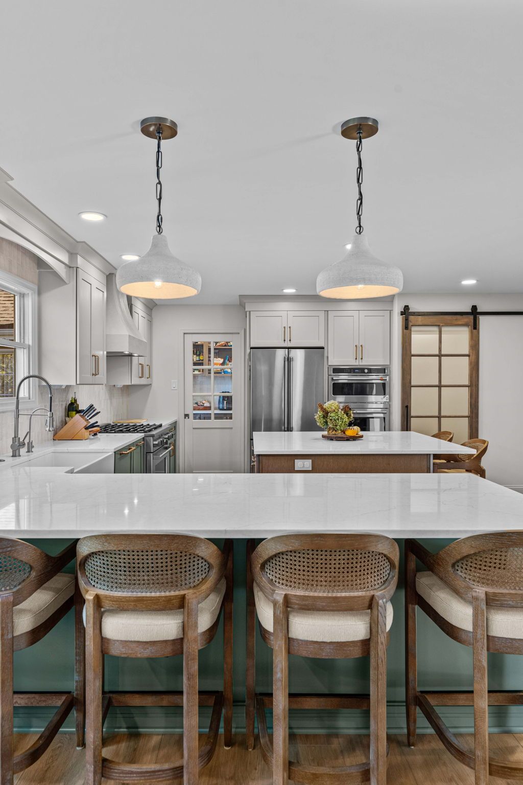 Bright modern kitchen with island, wicker bar stools, white cabinets, and pendant lights in Bucks Country PA
