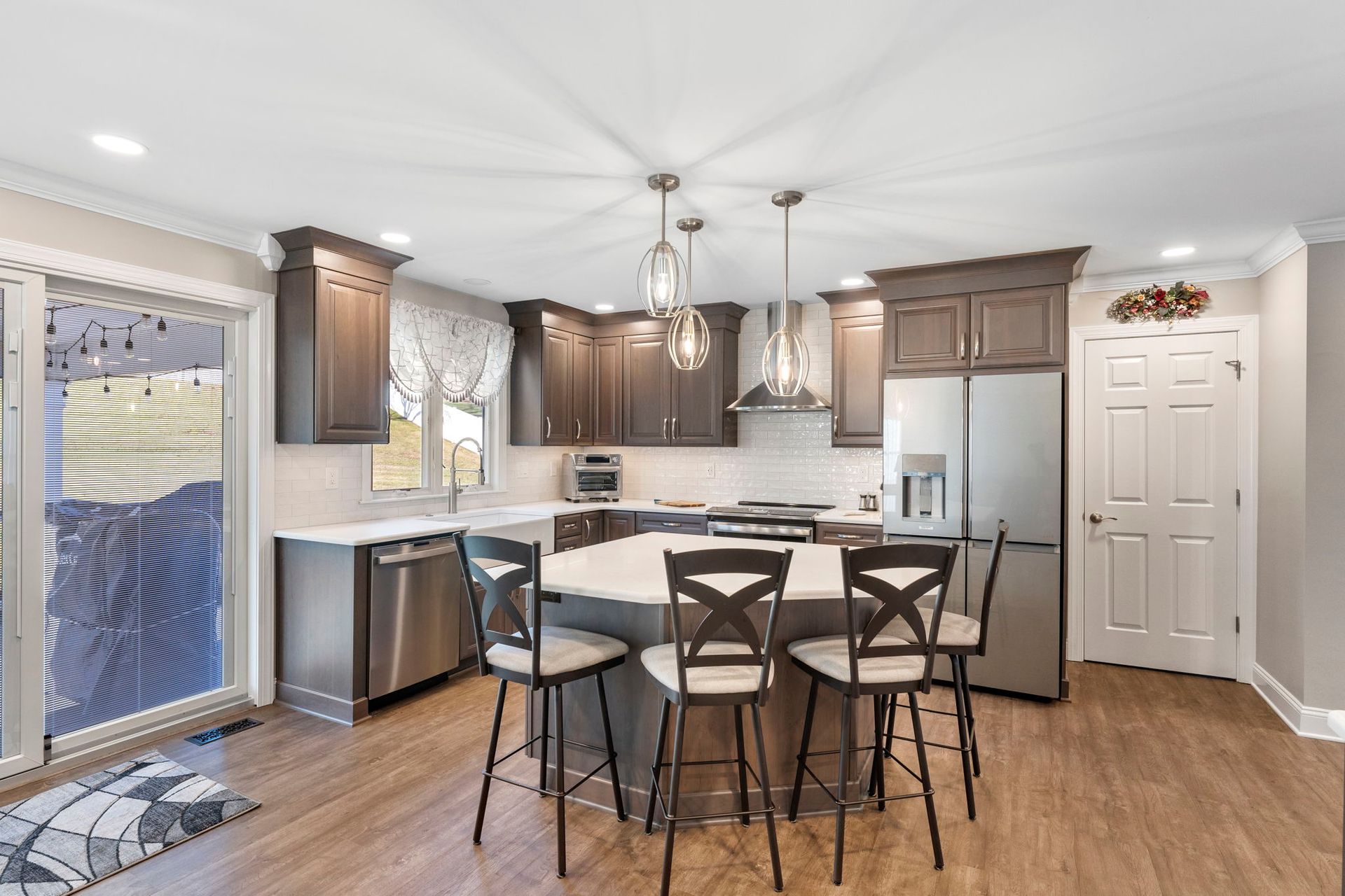 Bright kitchen with wood cabinets, white appliances, island seating, and a sliding glass door In Bucks Country PA