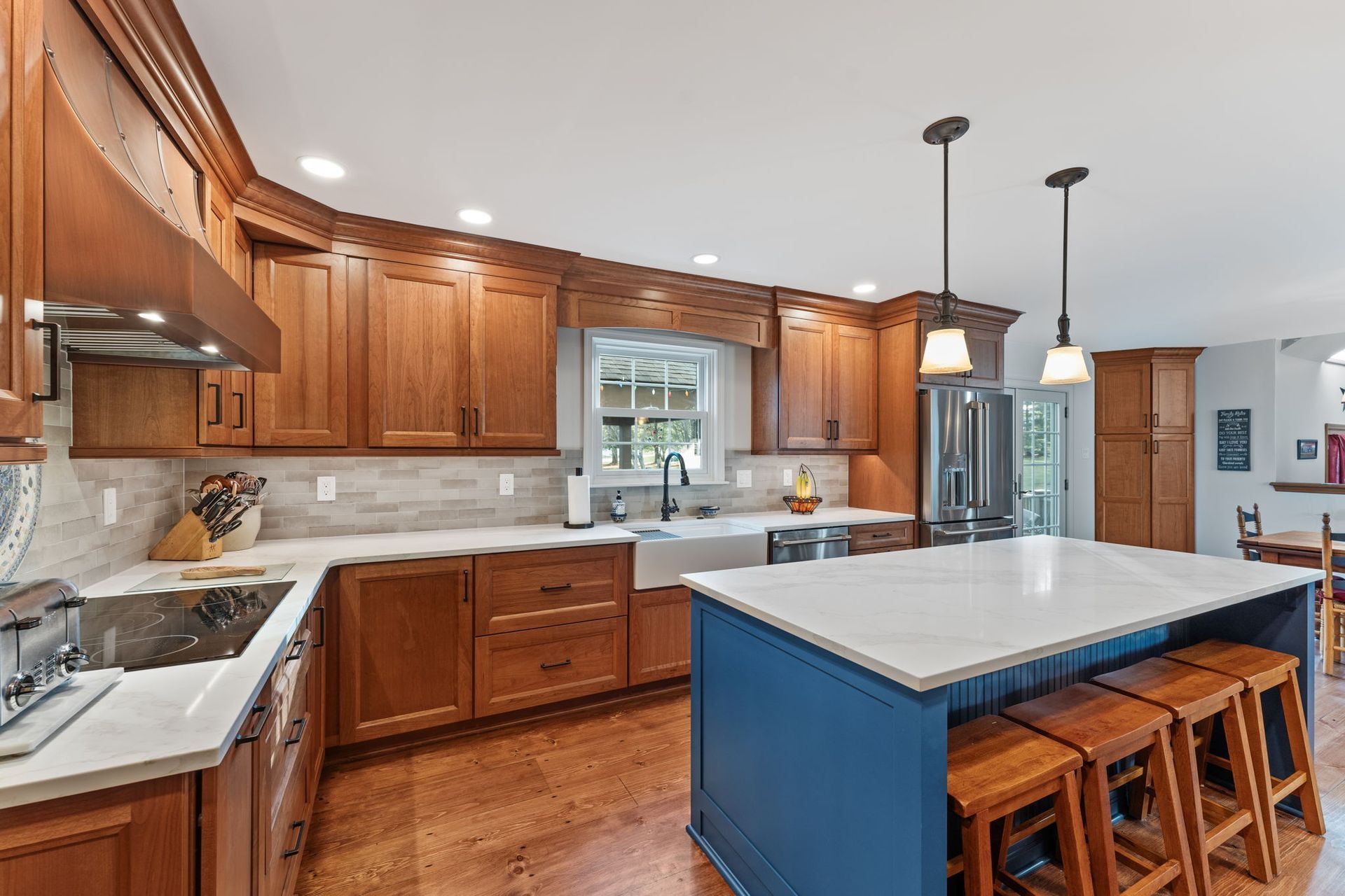 Bright kitchen with wooden cabinets, white countertops, blue island, and pendant lights In Bucks County PA