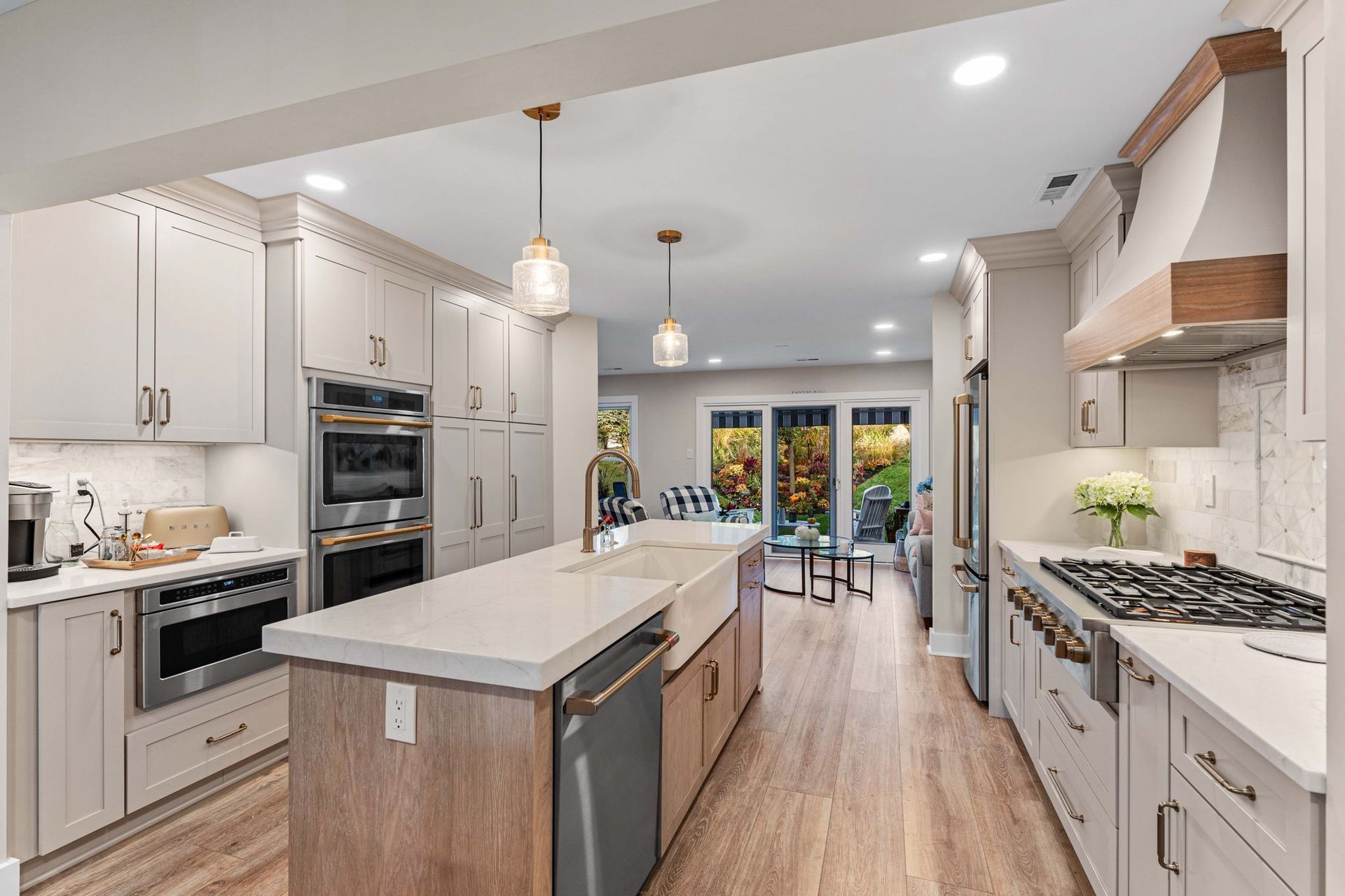 Bright modern kitchen with white cabinets, island, and stainless steel appliances leading to a patio door in Bucks County PA