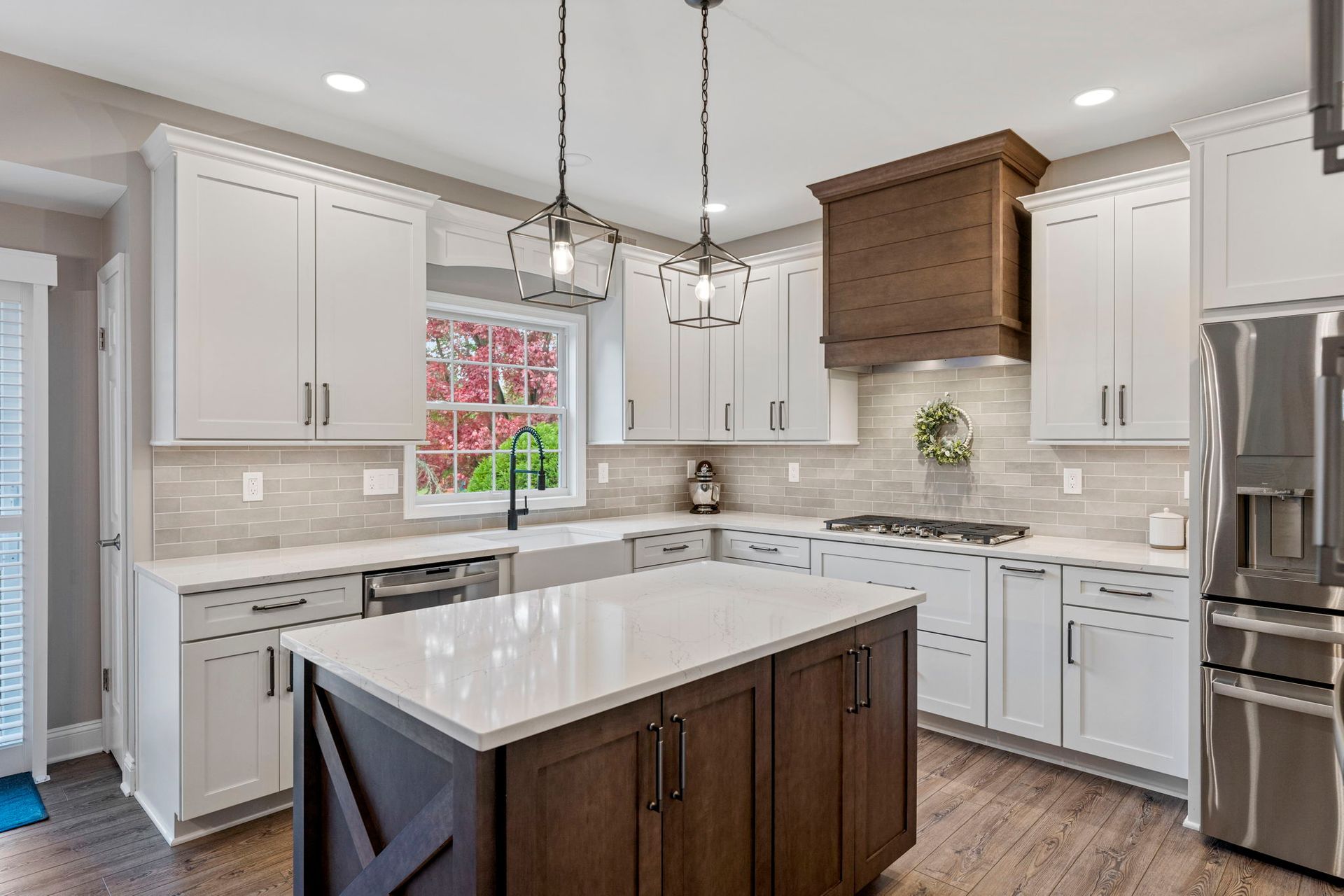 Modern white kitchen with dark wood island, stainless appliances, and pendant lights  In Bucks County PA