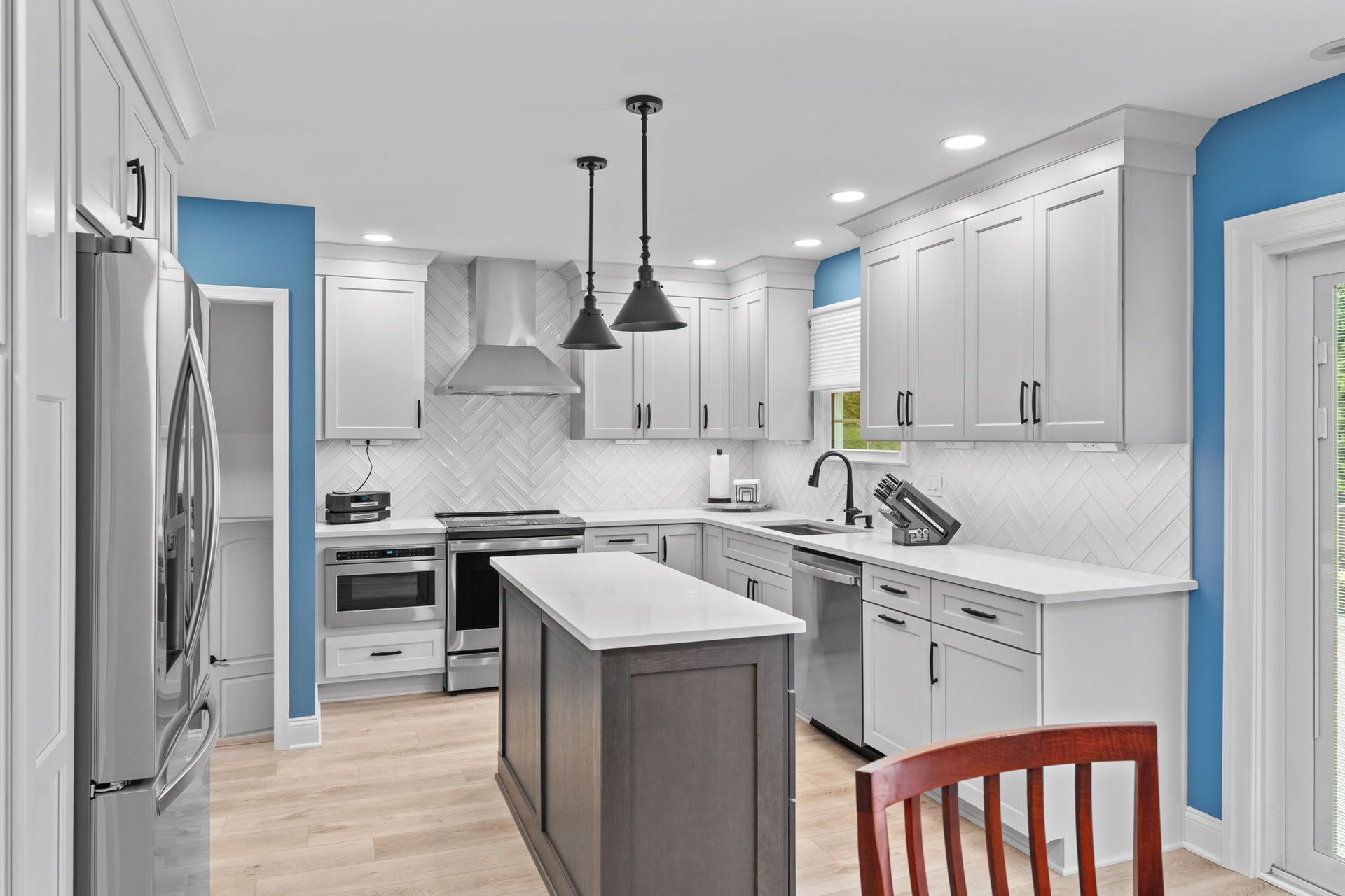 Bright white modern kitchen with island, stainless appliances, and blue accent wall in Bucks County PA