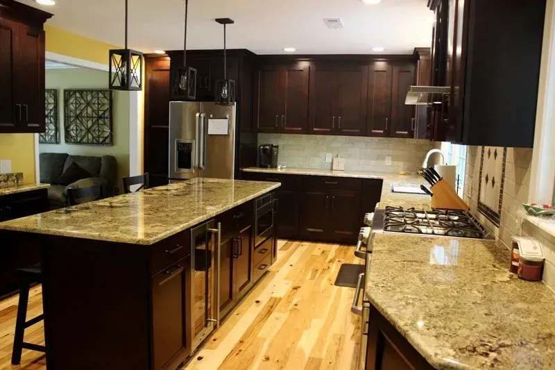 Modern kitchen with dark wood cabinets, stainless steel appliances, and granite countertops on a hardwood floor In Bucks Country PA