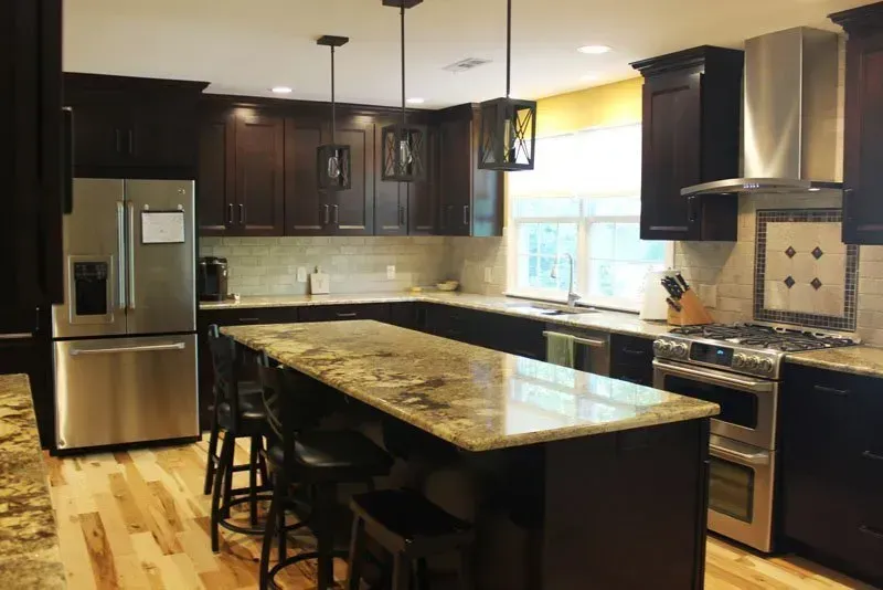 Modern kitchen with dark cabinets, granite island, stainless steel appliances, and pendant lights In Bucks County PA