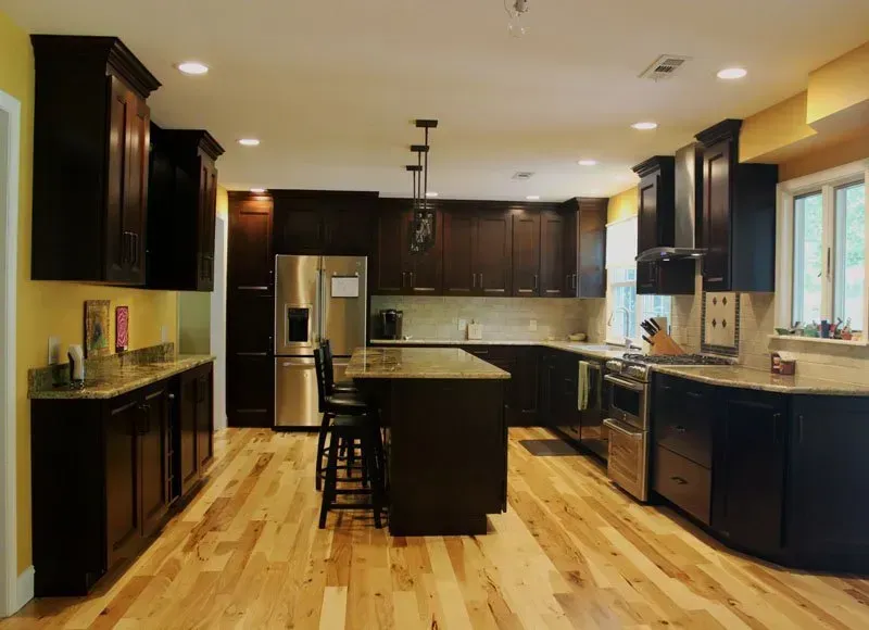Modern kitchen with dark wood cabinets, island, stainless steel appliances, and light hardwood floors In Bucks County PA