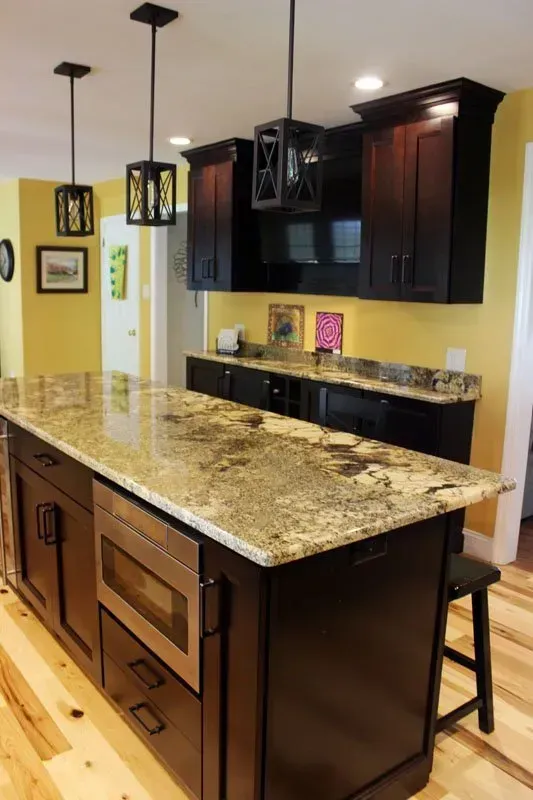 Modern kitchen with dark wood cabinets, granite island, and pendant lights In Bucks County PA