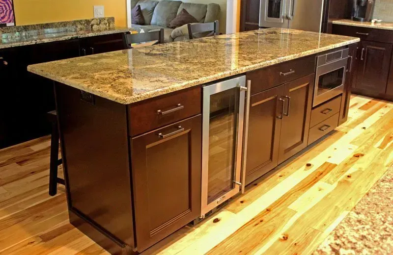 Kitchen island with dark wood cabinets and a speckled granite countertop on a hardwood floor In Bucks County PA