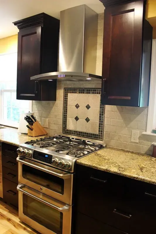 Modern kitchen with stainless steel stove, dark cabinets, and granite countertops In Bucks County PA