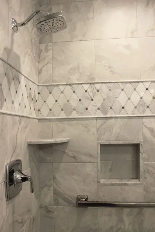 Tiled shower with chrome showerhead, corner shelf, soap niche, and grab bar In Bucks County PA