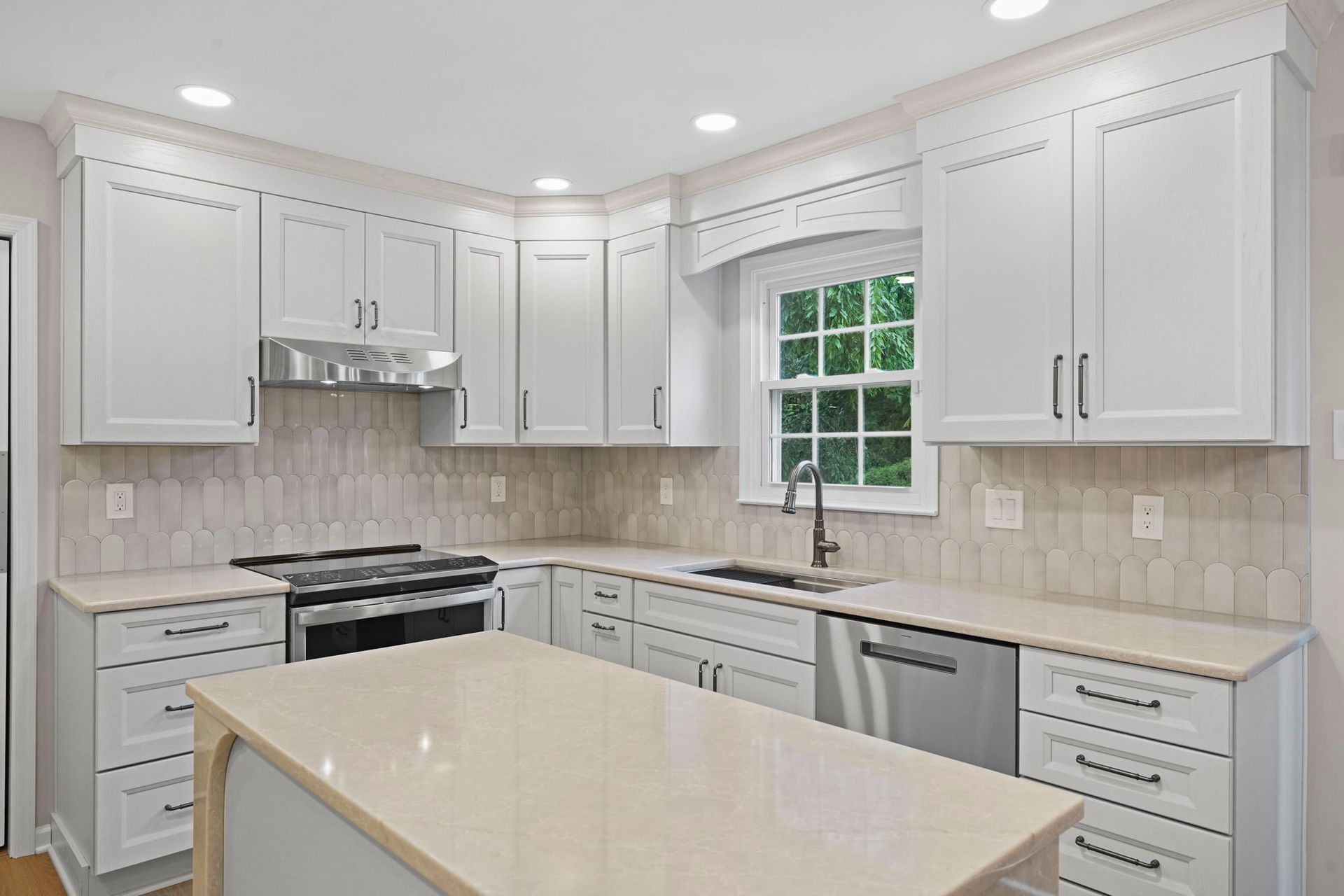 Bright white modern kitchen with island, stainless appliances, and beige tile backsplash in Langhorne