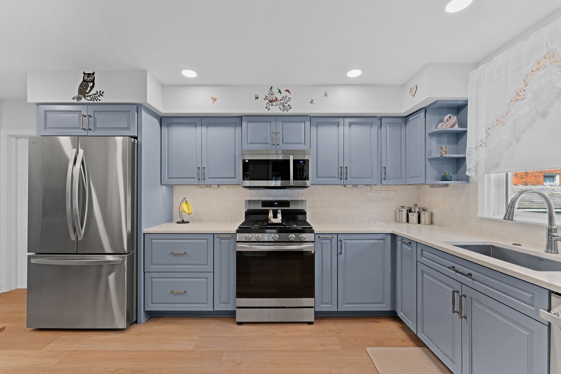 Modern kitchen with blue cabinets, stainless steel appliances, and a large sink under a bright window In Bucks County PA