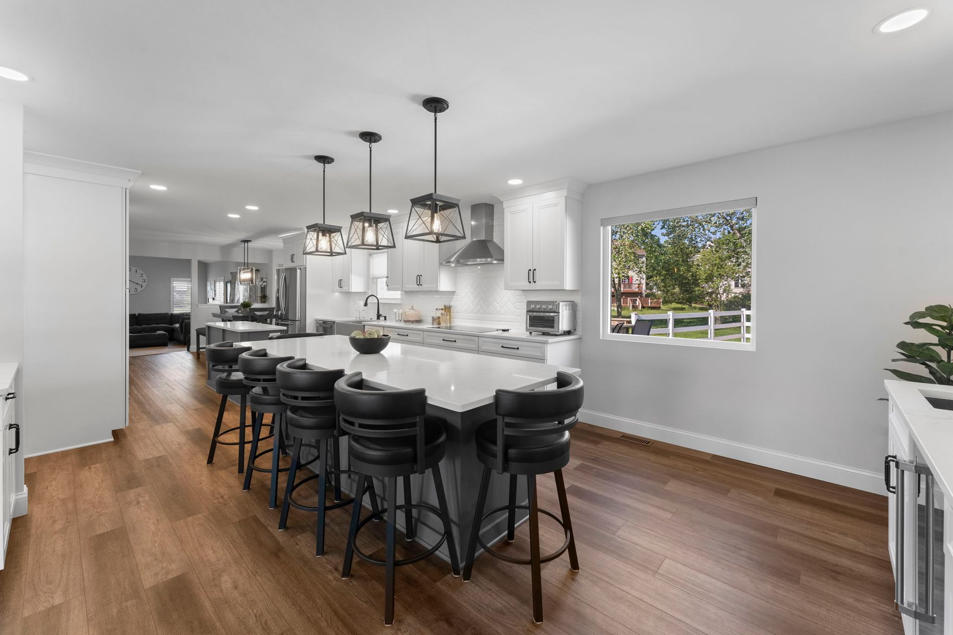 Modern kitchen with a large island, black stools, and hardwood floors, lit by pendant lights In Bucks County PA