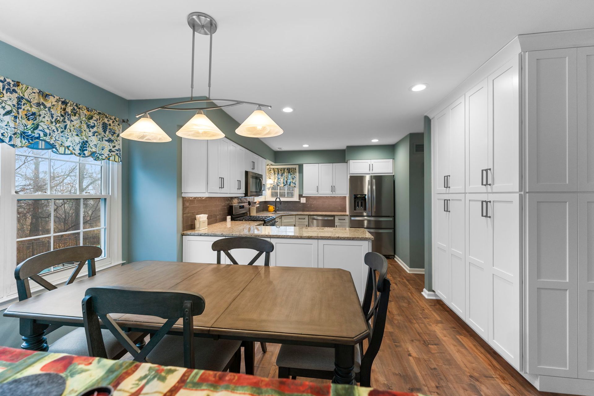 Bright dining room with wooden table, blue accent wall, kitchen pass-through, and white cabinets In Bucks Country PA