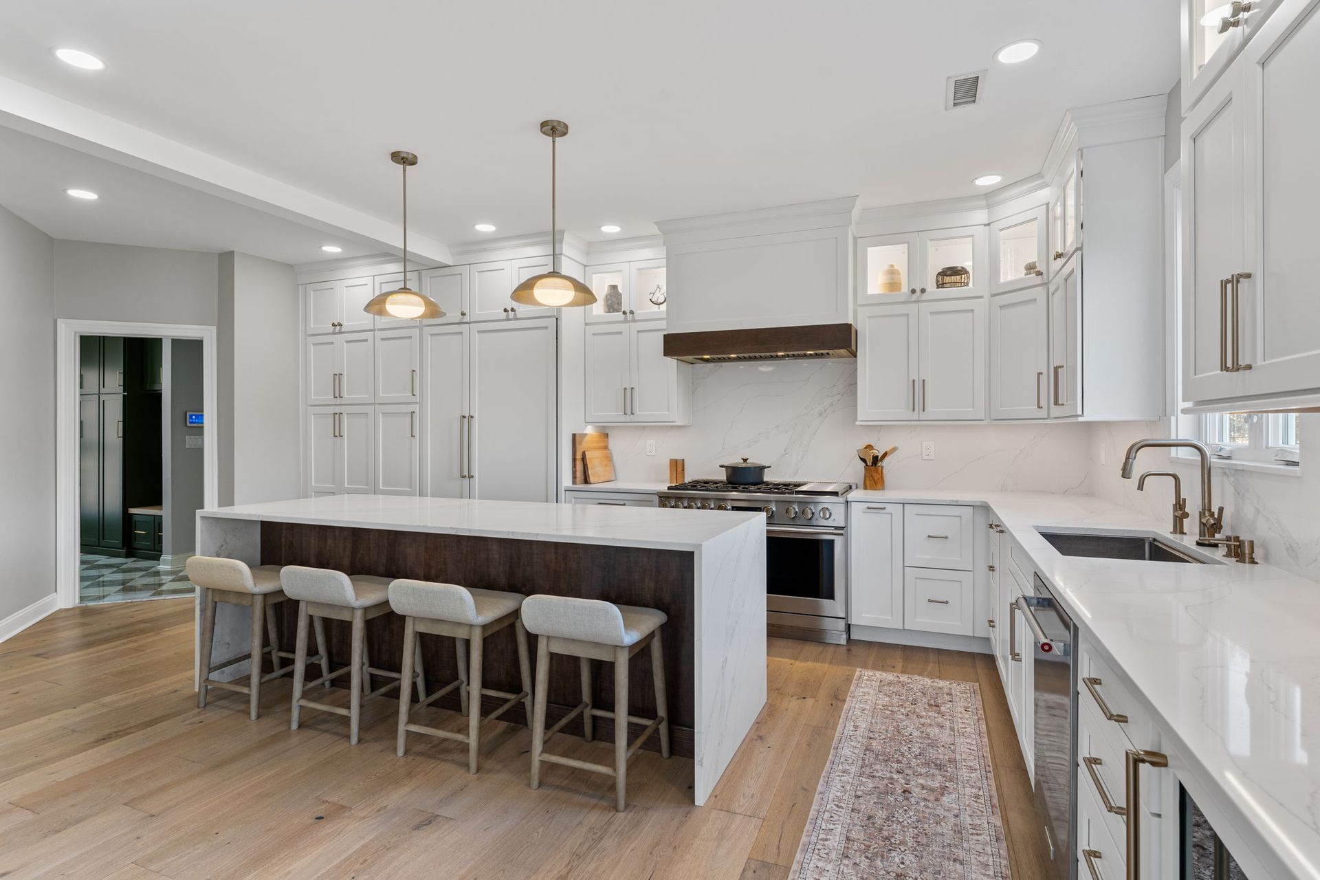 Bright modern white kitchen with island, pendant lights, barstools, and hardwood floors In Bucks County PA