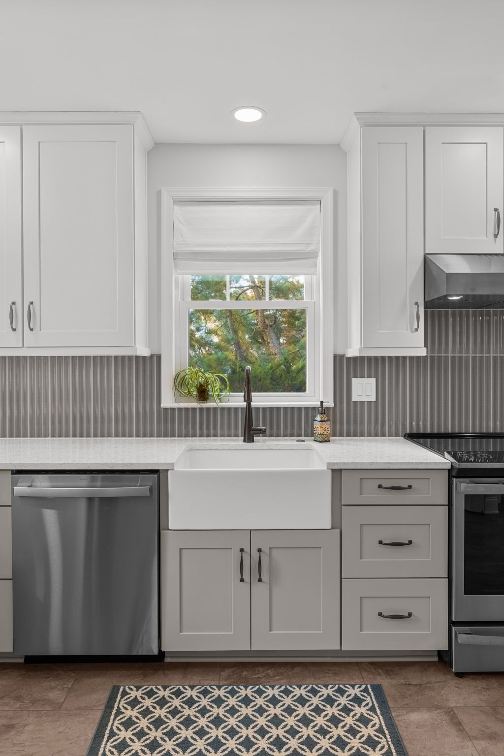 Modern kitchen with white cabinets, gray tile backsplash, farmhouse sink, and stainless steel appliances In Bucks County PA