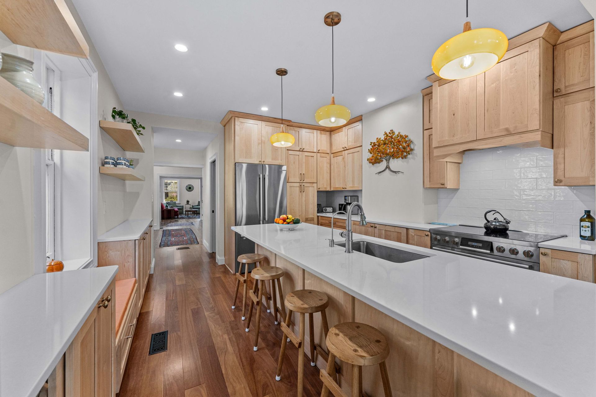 Bright modern kitchen with white island, wood cabinets, pendant lights, and bar stools In Bucks County PA