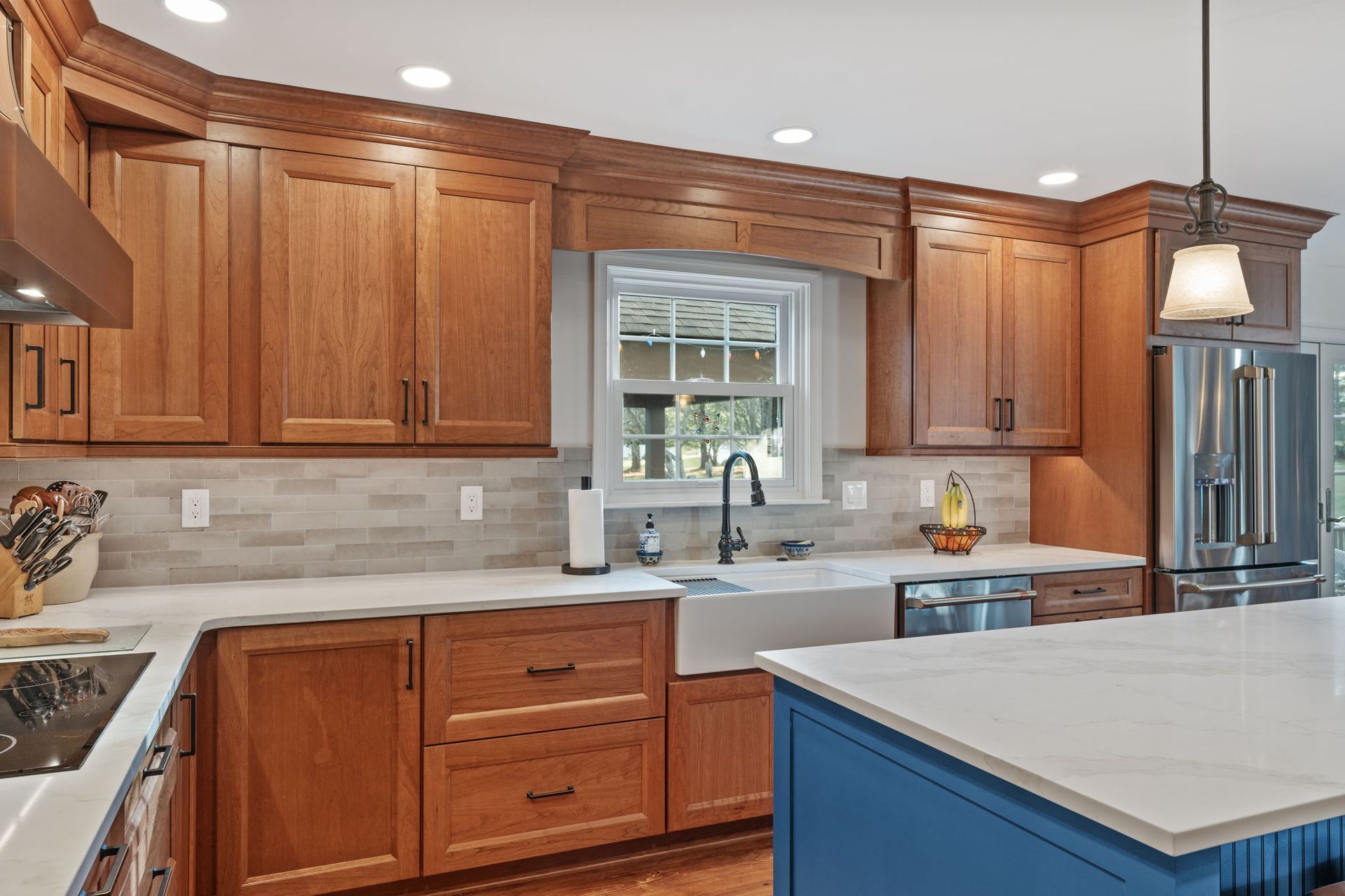 Modern kitchen with wood cabinets, stainless steel appliances, white countertops, and a blue island In Bucks County PA