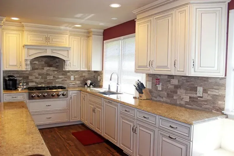 Bright kitchen with white cabinets, stone backsplash, granite countertops, and stainless-steel range In Bucks Country PA